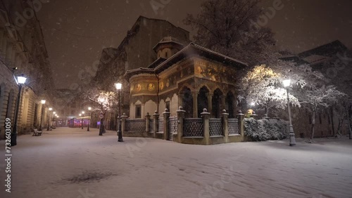 Winter in Bucharest. 4K video during a night snowfall on the streets of the city, view to Stavropoleos Monastery landmark building and the old town of the city. Travel to Romania. photo
