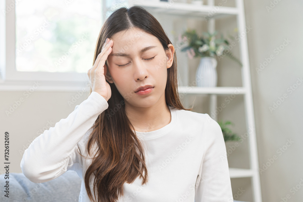 Dizzy asian young woman, girl headache or migraine pain suffering from vertigo while sitting on couch in living room at home, holding head with hand, health problem of brain or inner ear not balance. Dizzy asian young woman, girl headache or migraine pain suffering from vertigo while sitting on couch in living room at home, holding head with hand, health problem of brain or inner ear not balance.