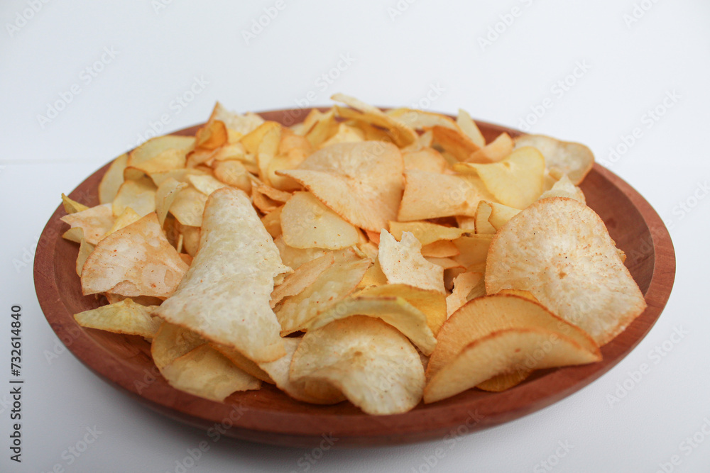 Cassava chips, in a wooden plate, isolated on white background