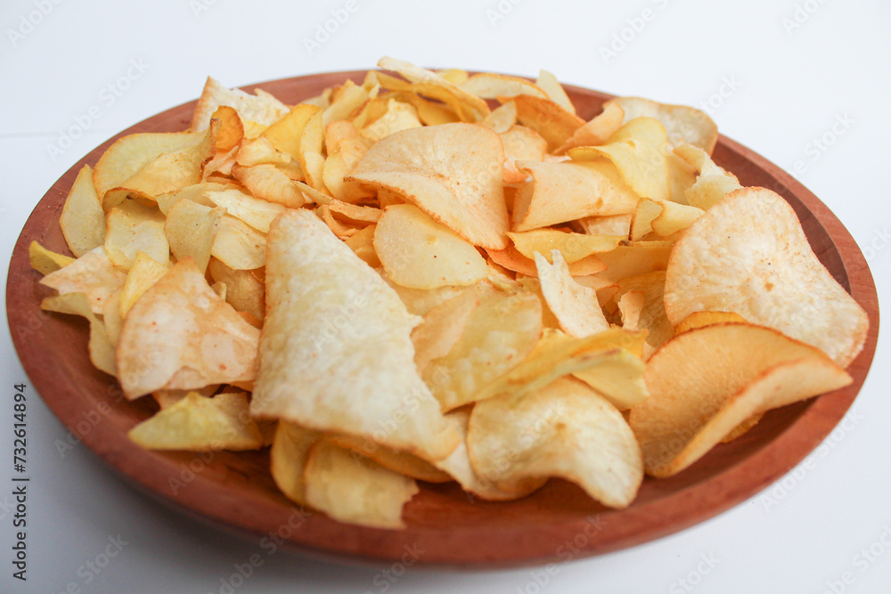 Cassava chips, in a wooden plate, isolated on white background Cassava chips, in a wooden plate, isolated on white background