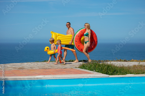 Kids and adults by pool, with inflatables, ready for swim day
