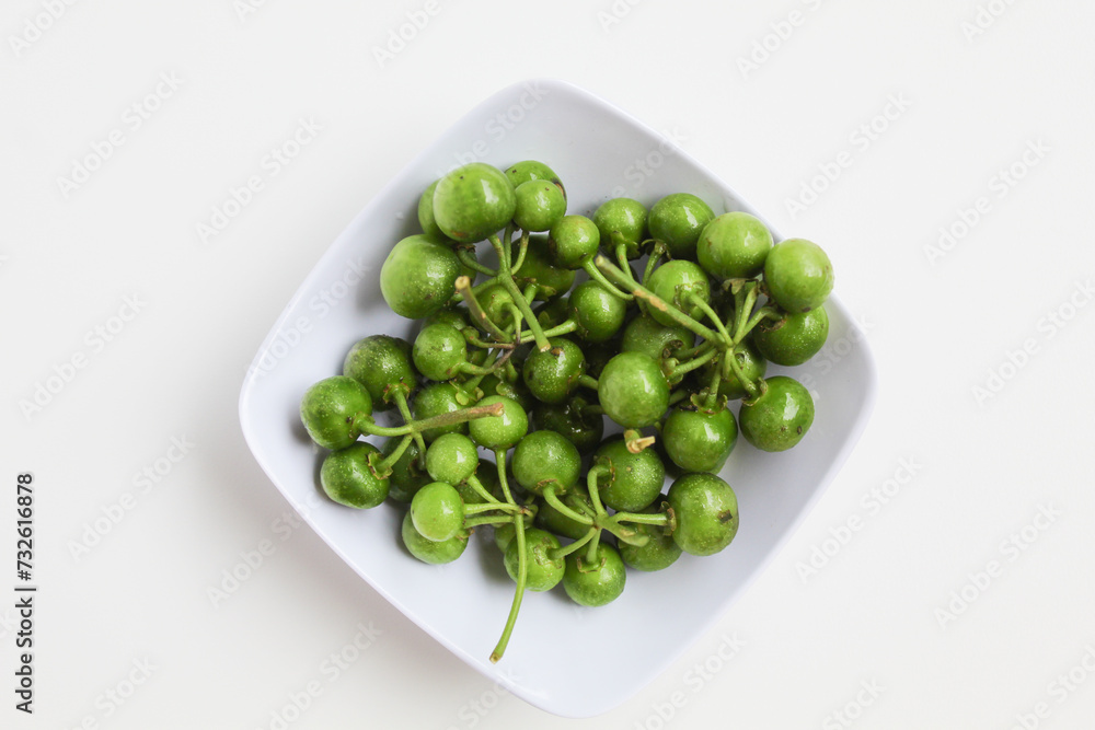 Fruit of Solanum nigrum, the European black nightshade or leunca, in a white bowl, isolated on white background, flat lay or top view Fruit of Solanum nigrum, the European black nightshade or leunca, in a white bowl, isolated on white background, flat lay or top view
