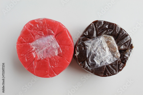 Nian gao, or year cake, is a sticky rice cake. In pink and chocolate color, wrapped in transparent plastic. Isolated on white background photo