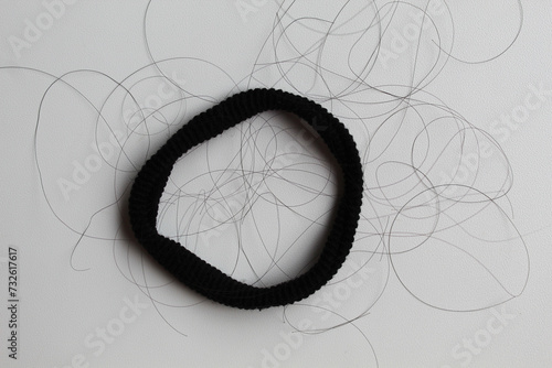 A black hair ties with strands of black hair. Hair loss or hair falling out or hair breakage