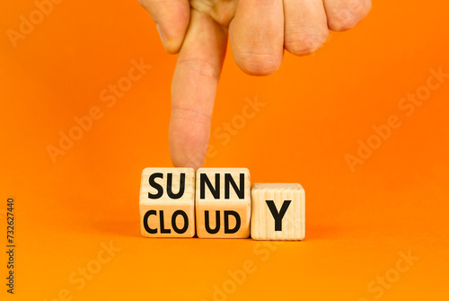 Sunny or cloudy symbol. Concept word Sunny or Cloudy on wooden cubes. Beautiful orange table orange background. Businessman hand. Business lifestyle and sunny or cloudy concept. Copy space.