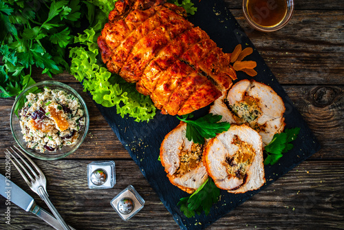 Stuffed turkey breast roulade with dried apricots and cranberries on wooden table
 photo