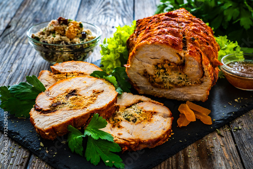 Stuffed turkey breast roulade with dried apricots and cranberries on wooden table 