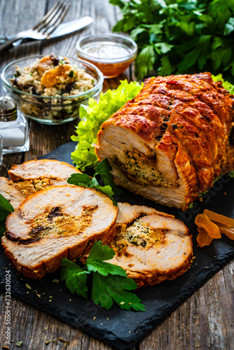 Stuffed turkey breast roulade with dried apricots and cranberries on wooden table 