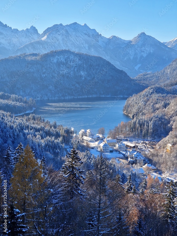 Germany, Bavaria, Allgäu, winter landscape with Hohenschwangau Castle and Lake Alpsee. Winter view of Lake Alpsee and Swiss Alps.Hohenschwangau castle, village and Alpsee lake with the mountain range Germany, Bavaria, Allgäu, winter landscape with Hohenschwangau Castle and Lake Alpsee. Winter view of Lake Alpsee and Swiss Alps.Hohenschwangau castle, village and Alpsee lake with the mountain range