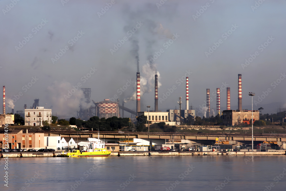 Acciaierie d'Italia steel industry (formerly Ilva, ArcelorMittal and Italsider). Pollution from chimneys on the Tamburi neighborhood of Taranto, Puglia, Italy Acciaierie d'Italia steel industry (formerly Ilva, ArcelorMittal and Italsider). Pollution from chimneys on the Tamburi neighborhood of Taranto, Puglia, Italy