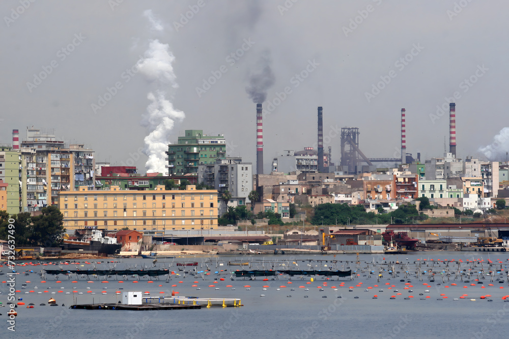 Acciaierie d'Italia steel industry (formerly Ilva, ArcelorMittal and Italsider). Pollution from chimneys on the Tamburi neighborhood of Taranto, Puglia, Italy