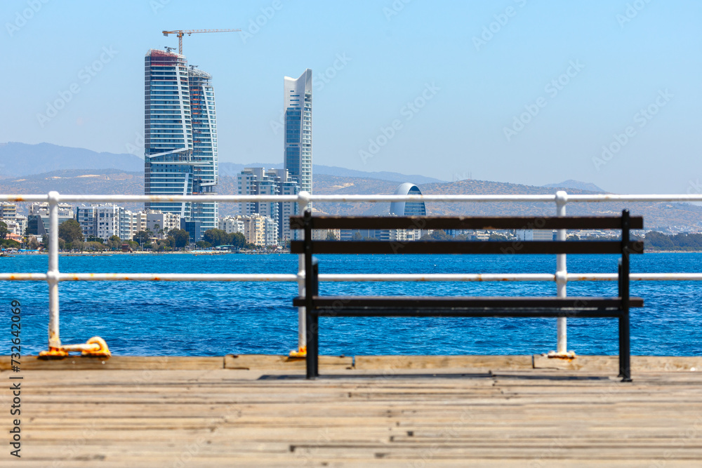 Wooden bench on the pier and modern skyscrapers in the background