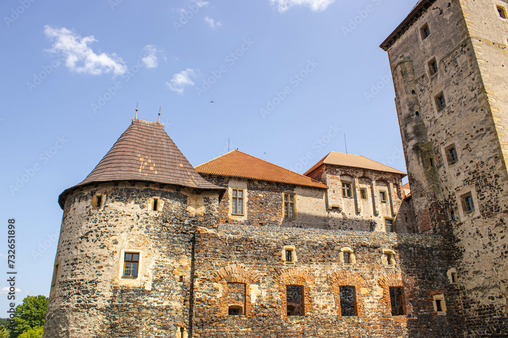 An old castle in the Czech Republic. Picturesque architecture of the Middle Ages. Against the background of the blue sky, the castle looks fabulous.