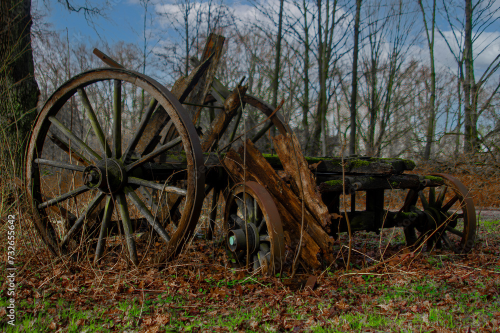 An old wooden wagon wheel is sitting in the grass