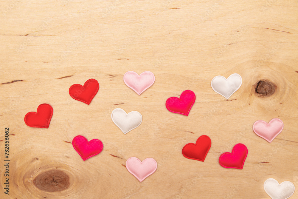 Obraz premium A lot of small hearts on wooden background with copy space. Greeting card with Enchanting love notes on textured wood.