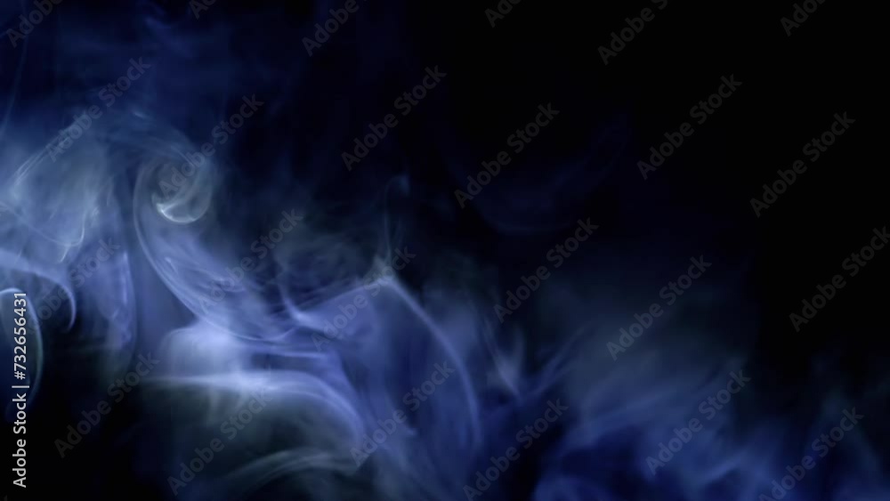 Thick Clouds of Blue Smoke Move in Rays of Neon Light in Empty Black Background. Whirlpool of Puffs of Icy Blue Vapor in Dense Fog. Texture. Abstract. Spin. Blurred motion. Smoking. Cigarette. Waves. Thick Clouds of Blue Smoke Move in Rays of Neon Light in Empty Black Background. Whirlpool of Puffs of Icy Blue Vapor in Dense Fog. Texture. Abstract. Spin. Blurred motion. Smoking. Cigarette. Waves.