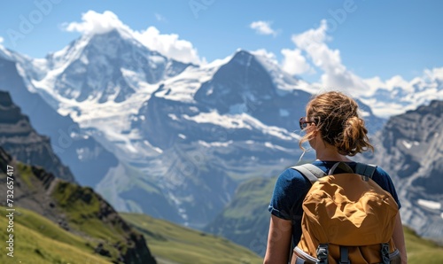 Swiss Alpine Adventure: A Happy Tourist Woman, Backpack-Clad, Revels in the Daytime Splendor of Jungfraujoch, Marveling at the Panoramic Views and Snow-Capped Peaks in the Swiss Alps.
