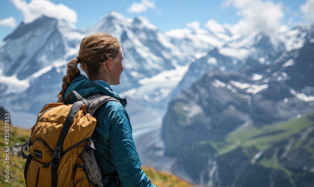 Swiss Alpine Adventure: A Happy Tourist Woman, Backpack-Clad, Revels in the Daytime Splendor of Jungfraujoch, Marveling at the Panoramic Views and Snow-Capped Peaks in the Swiss Alps.




