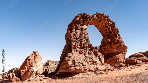 Tadrart landscape in the Sahara desert, Algeria. A delicate red sandstone arch has been sculpted by the wind and sand of the Tadrart