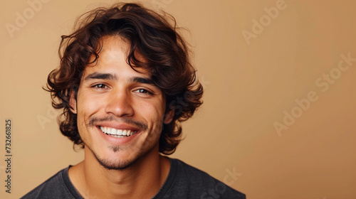 A Handsome Mexican Man With Wavy Hair And A Cheerful Smile, Isolated On A Khaki Background © Wassim