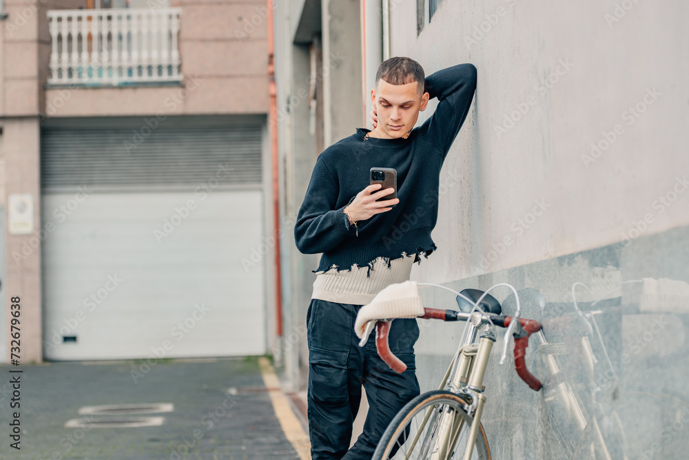 Fototapeta premium fashionable young man with mobile phone and bicycle in urban background