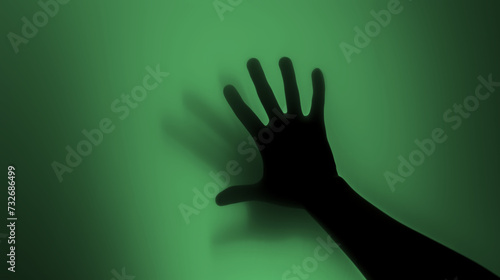 Hand silhouette on green background. Blurred human hand shape out of focus