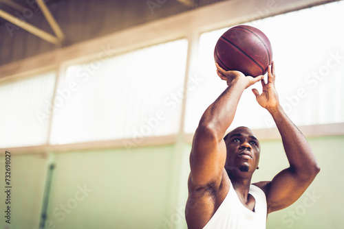 Man shooting basketball in indoor gym photo