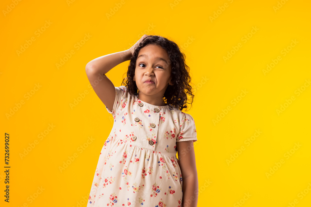 Doubtful kid girl scratching her head over yellow background. Uncertainty concept Doubtful kid girl scratching her head over yellow background. Uncertainty concept