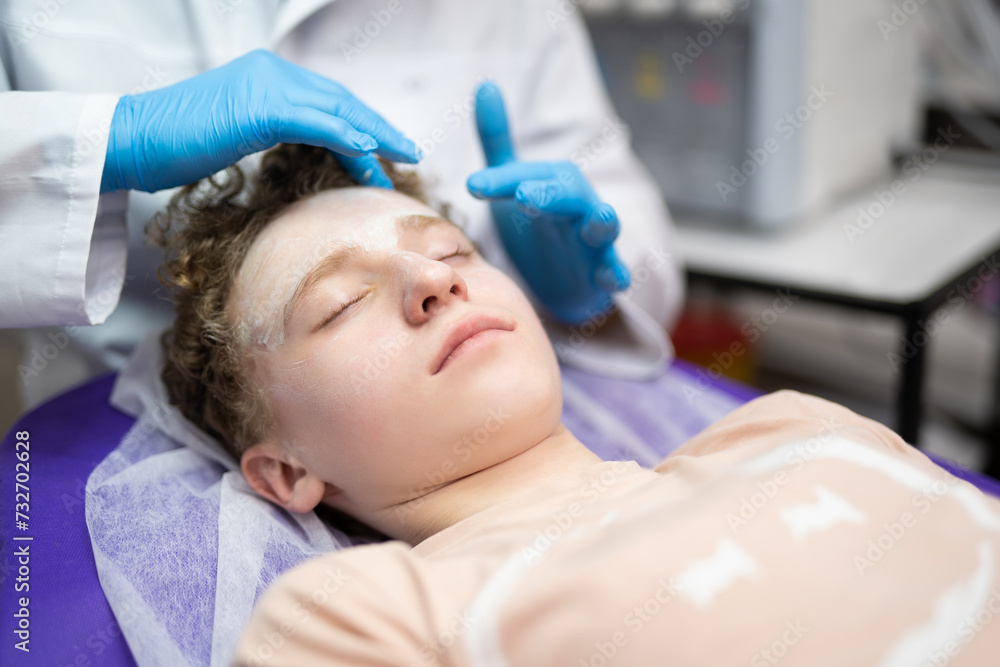 a cosmetologist doctor makes cosmetic procedures on the face of a young guy in a beauty salon a cosmetologist doctor makes cosmetic procedures on the face of a young guy in a beauty salon