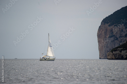 Barca a vela in navigazione nella rada di Porto conte. Sullo sfondo il promontorio di Capo Caccia. Alghero, Sardegna. Italia photo