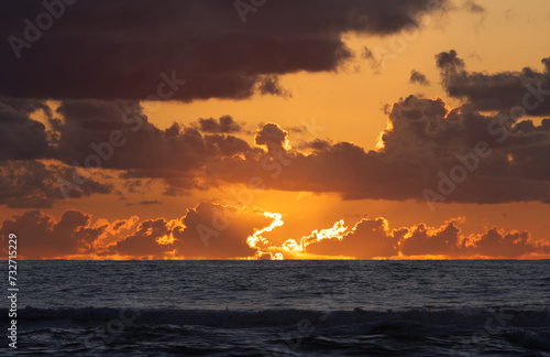 Sundown over the pacific ocean with glowing sun rays and deep orange hues
