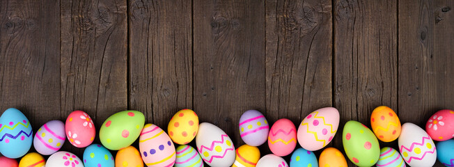 Colorful Easter Egg bottom border over a dark wood banner background. Copy space.