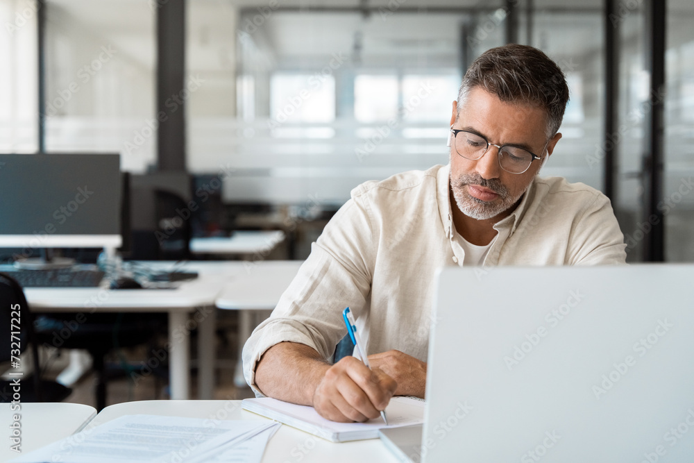 Focused middle-age Hispanic man using laptop computer for business studying, watch online virtual webinar training meeting, video call, make notes. Mature Latin businessman work in office, copy space. Focused middle-age Hispanic man using laptop computer for business studying, watch online virtual webinar training meeting, video call, make notes. Mature Latin businessman work in office, copy space.