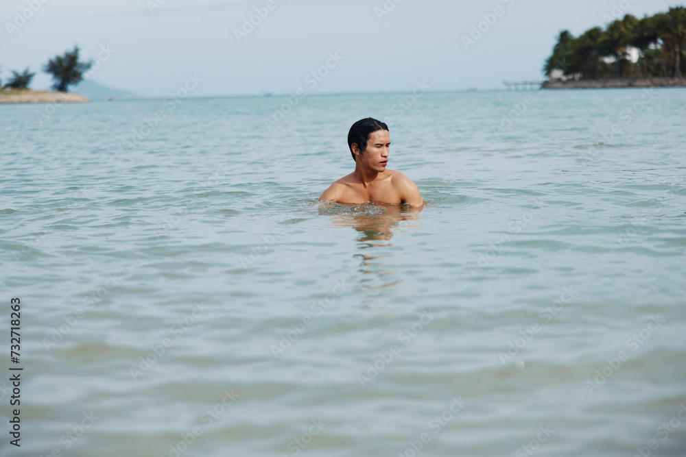 Smiling Asian Man Enjoying a Tropical Swim in the Ocean, Embracing the Freedom and Happiness of a Beach Vacation