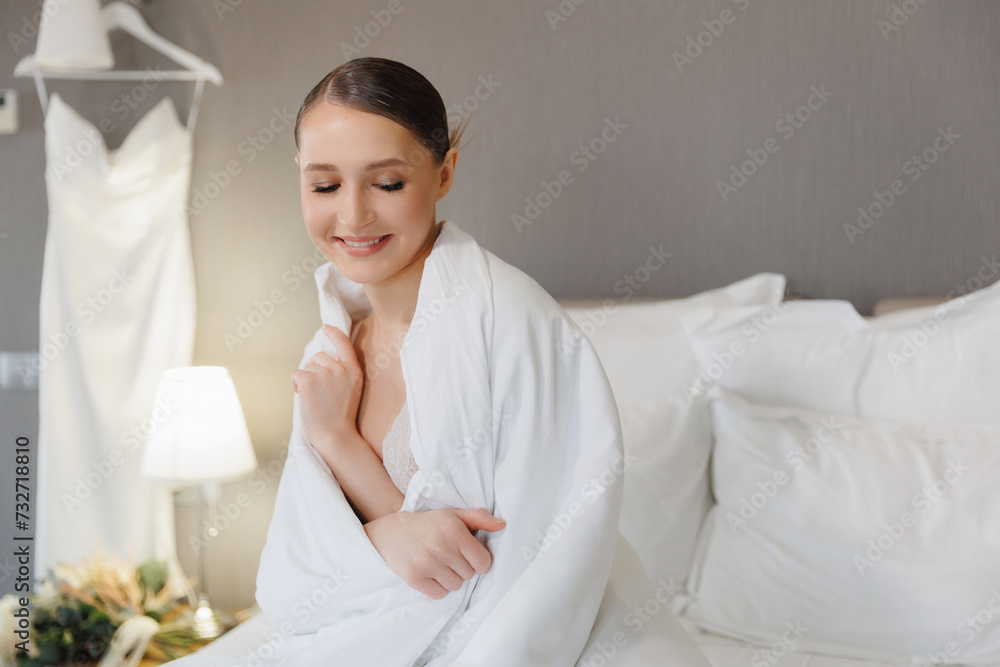 Smiling Woman Wrapped in White Duvet Sitting on Bed in Modern Room of hotel, concept wedding morning Smiling Woman Wrapped in White Duvet Sitting on Bed in Modern Room of hotel, concept wedding morning