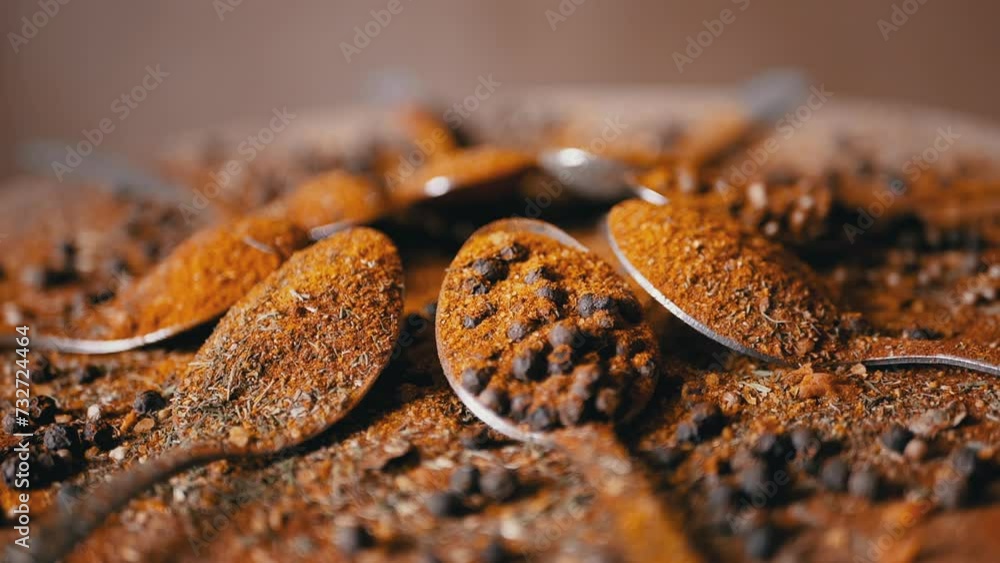 Spoons with Indian Spices Rotate on a Colorful, Wooden Background. Close up. Slow motion. Scattered spice mix, grains black peppercorns, turmeric, paprika, coriander, oregano. Backgrounds, texture. Spoons with Indian Spices Rotate on a Colorful, Wooden Background. Close up. Slow motion. Scattered spice mix, grains black peppercorns, turmeric, paprika, coriander, oregano. Backgrounds, texture.