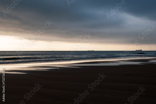 Sunset on the beach in Normandy, France, with a ship in the background