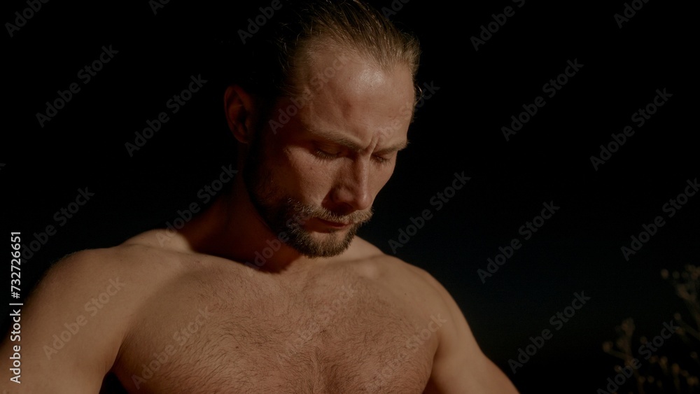Shirtless barbarian resting in camp at night Shirtless barbarian resting in camp at night