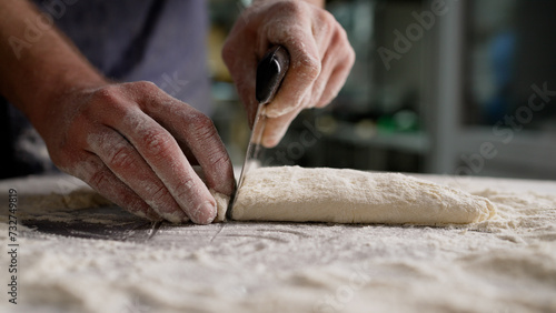Close-up of a baker's hands making baking dough. Male chef's hands roll out dough close-up. Male hands roll out dough with a wooden rolling pin.