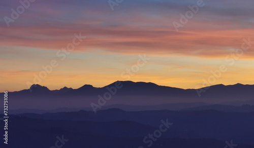 Tramonto blu e arancio con luna nel cielo sopra le valli e le montagne © GjGj