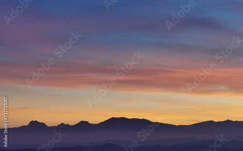 Tramonto blu e arancio con luna nel cielo sopra le valli e le montagne