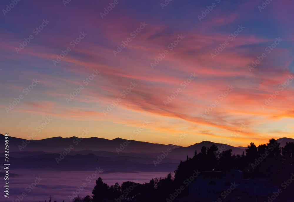 Le valli tra monti si riempiono nel rosso tramonto di un mare di nuvole