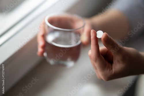 woman hands holding capsule pill and glass of water close up 