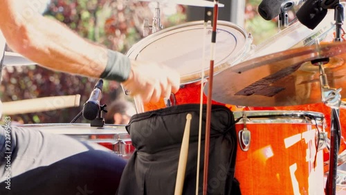 Side view of drummer playing on the stage on a summer music festival at the park.