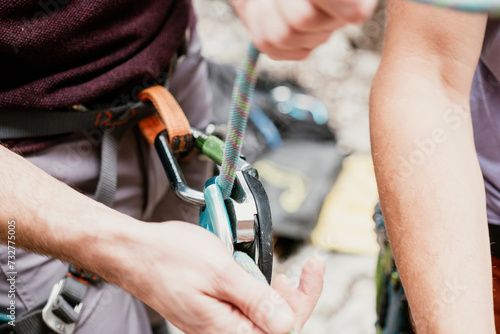 unrecognizable hand secures a carabiner in a rope harness photo