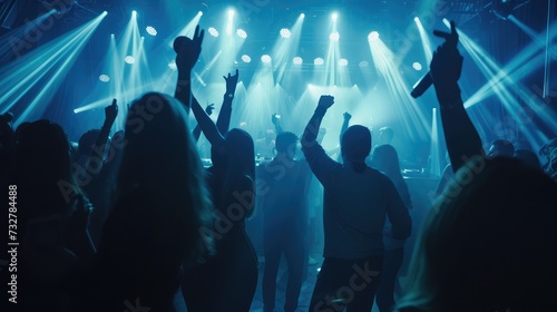 Happy people dance in nightclub light party concert bar and listen to the night music from DJ on the stage in the background