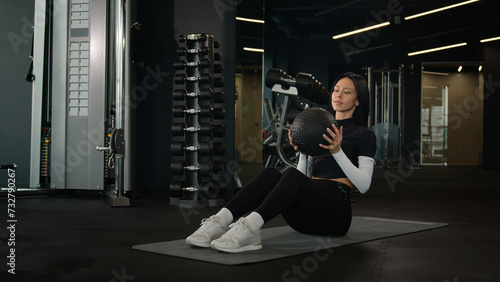 Fit girl Caucasian woman fitness trainer active workout on floor twisting exercise throw ball strong healthy female sportswoman training abs abdominal muscles exercising with equipment in sport club
