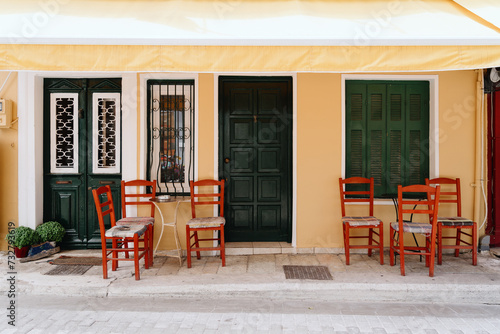 Colorful chairs and a welcoming green door at a quaint Mediterranean street cafe