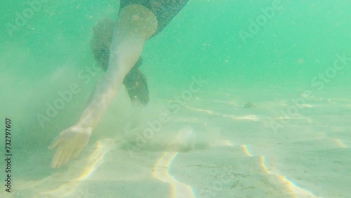 Pregnant, beautiful woman in a black swimsuit swims underwater in the tropical sea, in which the rays of the sun play. Healthy and active pregnancy concept. Water activities, travel during pregnancy