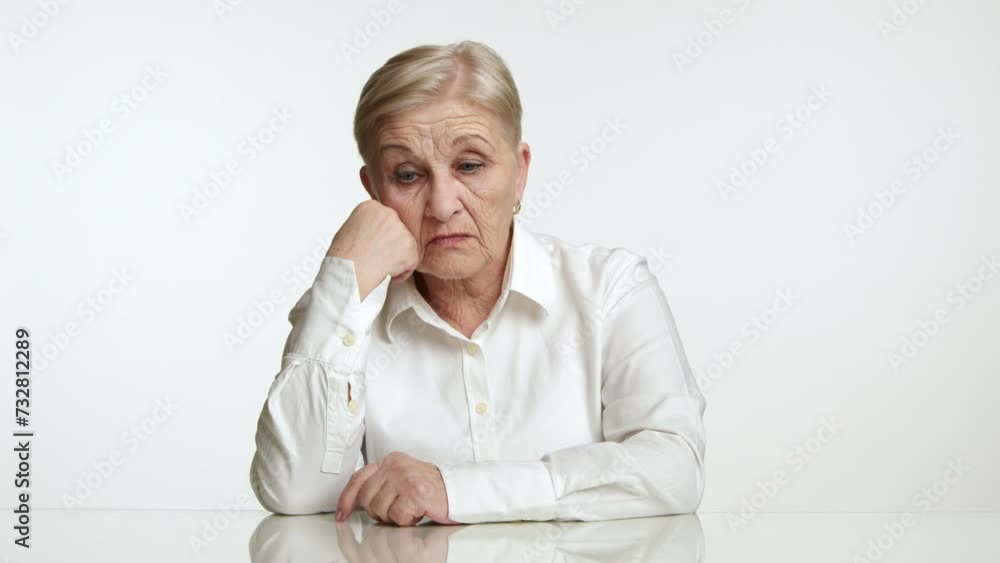 Elegant short-haired old lady in white shirt sleeping at table with fist under chin, opening eyes, looking suspiciously, feeling distracted, white studio. High quality 4k footage Elegant short-haired old lady in white shirt sleeping at table with fist under chin, opening eyes, looking suspiciously, feeling distracted, white studio. High quality 4k footage